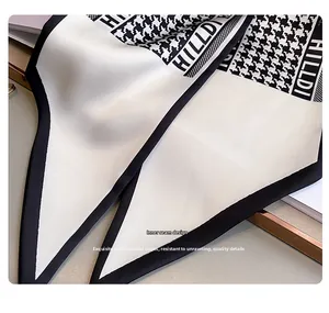 Macro detail of houndstooth silk scarf showing refined inner stitching and HILLDI logo