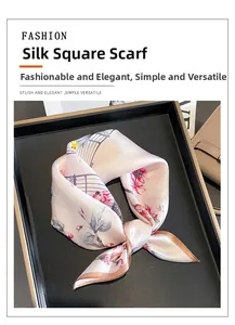 Detail of a pink silk square scarf with floral pattern tied elegantly on a display tray