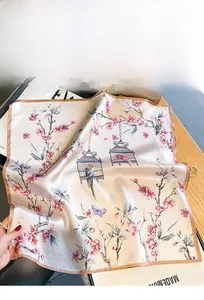 Flat lay of elegant silk square scarf with vintage floral, birdcage and butterfly patterns