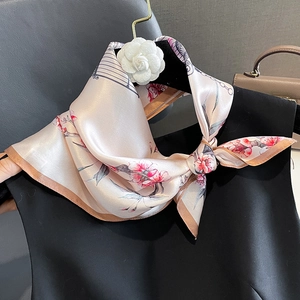 Elegant silk scarf featuring pink floral patterns and birdcage prints tied on a black outfit