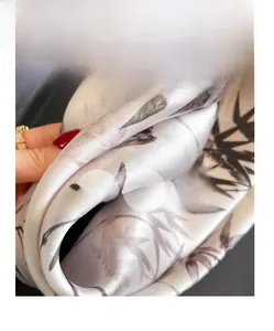 Détail d'un foulard en soie montrant une texture lisse et des motifs de bambou