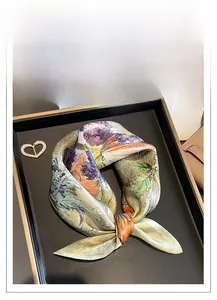 Artistic floral silk square scarf with purple and orange prints on a luxury tray