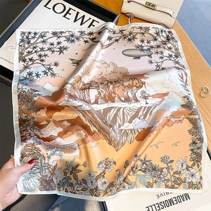 Silk square scarf with jungle landscape print and floral details on a wooden table