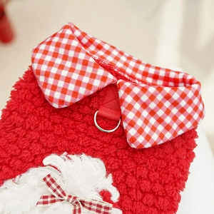 Macro detail of red fleece pet vest featuring harness D-ring and plaid collar