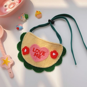 Détail d'un bavoir tricoté jaune pour animaux avec broderie Love Me et dentelle