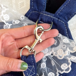Close-up of silver metal clasp on blue denim pet dress with white lace trim details