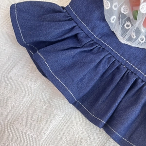 Detail of dark blue denim pet dress featuring white contrast stitching and lace trim