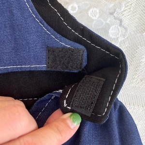 Detail of blue denim pet dress with secure black trim and adjustable velcro fastener