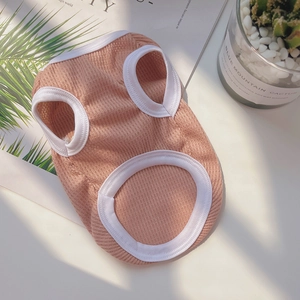 Close-up of pink-orange ribbed knit pet vest with white edge stitching and soft texture