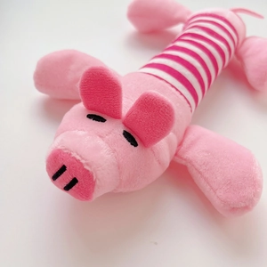 Detail eines rosa Plüsch-Schweinchens für Hunde mit Streifenstoff und Stickerei