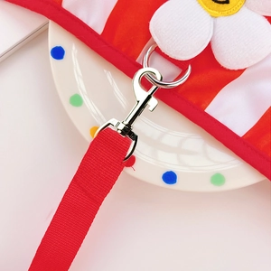 Detail of red striped pet harness with smiling daisy flower and silver metal swivel hook
