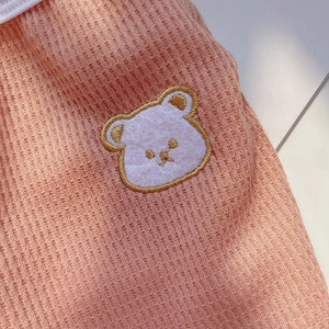 Close-up of pink waffle knit fabric with a cute cartoon bear embroidery patch