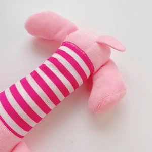 Detail eines rosa Plüsch-Hundespielzeugs mit weichem Streifenstoff und süßer Stickerei
