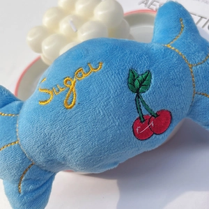 Macro detail of plush candy dog toy with Sugar embroidery and soft blue fabric