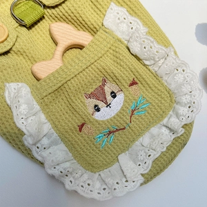 Detail von grünem Waffelstoff-Haustiergeschirr mit Eichhörnchenstickerei und Spitze