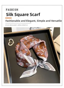 Detail of paisley silk scarf folded on a display tray with elegant brooch and wallet