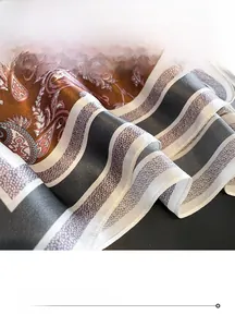 Macro detail of silk scarf showing refined paisley pattern and professional rolled edges