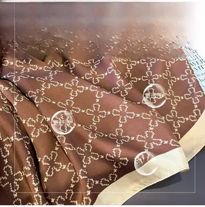 Detailed close-up of brown imitation silk scarf with white clover print and satin edges