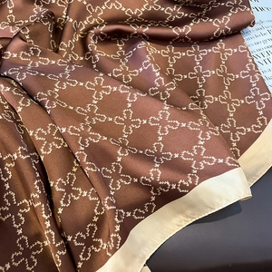 Elegant brown silk scarf with white clover patterns and cream border shown in soft folds