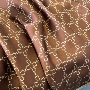 Silky dark brown scarf with white geometric clover patterns and elegant glossy finish