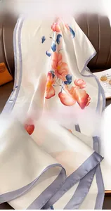 Detailed close-up of orange magnolia floral scarf with premium stitched edge finish