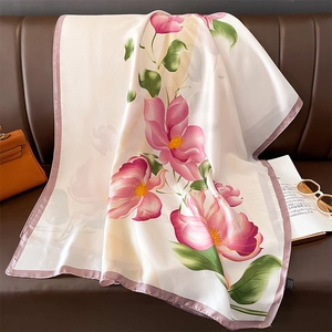 Detailed close-up of a floral silk scarf with pink magnolias on a luxury leather sofa