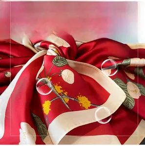 Macro detail of red faux silk scarf showing vibrant camellia floral prints and satin texture
