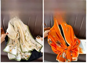 Detailed view of floral silk scarves in beige and orange on a textured leather surface