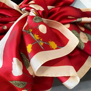 Detailed close-up of red silk scarf with white camellia print and satin texture
