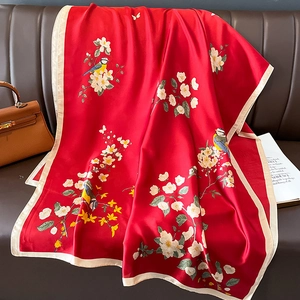 Red silk scarf with camellia and bird print on a dark sofa with glossy finish