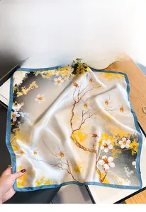 Close-up of mulberry silk square scarf featuring yellow floral patterns and blue hem edge