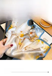 Detail of premium silk scarf featuring yellow floral patterns and blue stitched edges