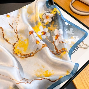 Artistic floral mulberry silk square scarf with hand-rolled edges on a wooden table