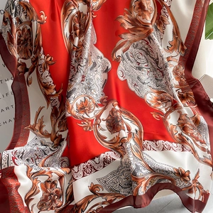 Close-up of vintage floral silk scarf featuring intricate baroque patterns in red and gold