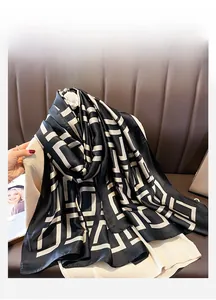 Detailed view of long silk scarf with geometric pattern draped over a cardigan
