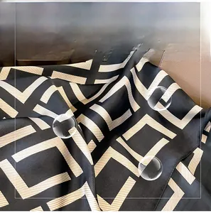 Detail of silk-like scarf featuring black and white geometric patterns and satin texture