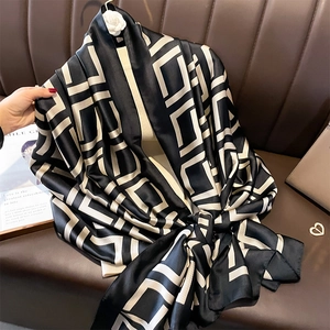 Luxurious geometric silk shawl scarf styled over a beige top with a camellia brooch