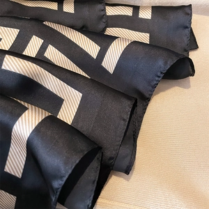 Elegant silk satin scarf with black and gold geometric patterns in a soft draped view