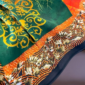 Close-up of silk scarf showing green baroque patterns and orange geometric prints