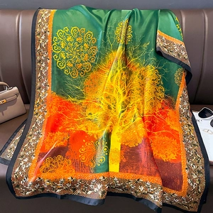 Elegant silk-like scarf with green to orange gradient and Tree of Life print on leather sofa