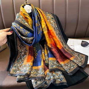 Elegant multi-color floral print silk scarf styled with a black coat and camellia brooch