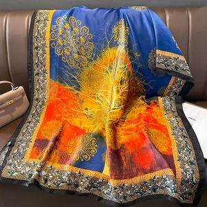 Detail of silk scarf with golden tree of life print draped on a leather sofa