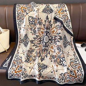 Elegante sciarpa in seta con stampa paisley e dettagli arancioni su divano in pelle