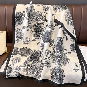 Elegant ivory floral silk scarf with vintage black pattern and borders on leather sofa