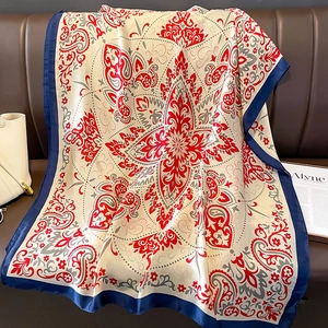 Sciarpa di seta con motivi paisley e bordo blu scuro su un divano in pelle