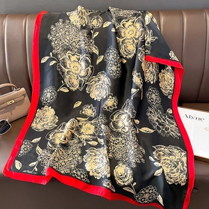 Detail of vintage floral silk scarf with red border draped on a luxury leather sofa