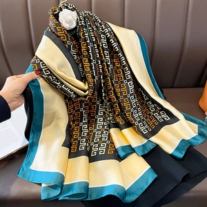 Elegant geometric silk scarf with Greek key pattern and camellia brooch on leather sofa
