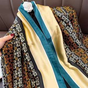 Detail of silk-like scarf featuring geometric patterns and camellia flower ornament