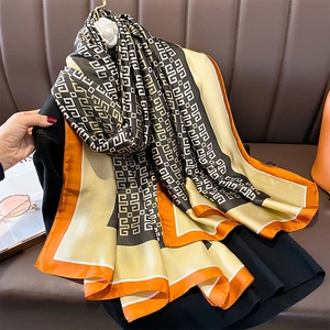 Orange and gold geometric silk shawl with G-pattern on a brown leather background