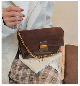 Détail du sac à main en cuir marron vintage avec chaîne dorée posé sur un livre